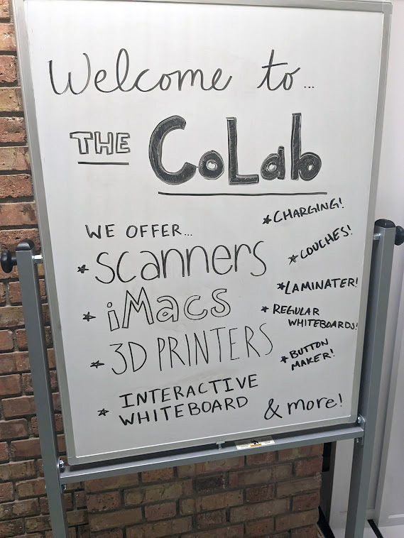 Photo of Sign: Welcome to the Colab. We offer: Scanners, iMacs, 3D Printers, Interactive Whiteboard.