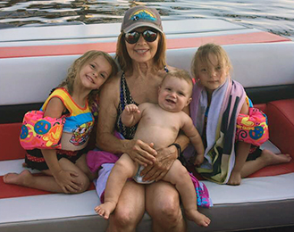 Photo: Mary seated in a boat holding baby grandchild and flanked by 2 more grandchildren