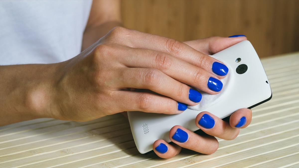 Photo: Female hands cleaning cell phone